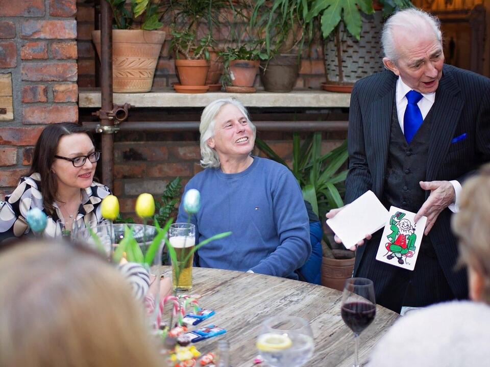 Pat Fallon entertaining guests with close-up magic at a garden party table